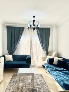 MadinatyGrand Madinaty 2BR Home-EID Mubarak的客厅配有蓝色的沙发和吊灯。