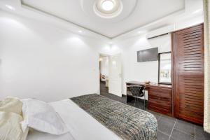 杜阿拉Cosy Home的一间卧室配有一张床、一张书桌和一台电视