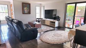 黄金海岸Kumera Home的客厅配有黑色真皮座椅和平面电视
