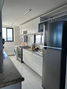 萨尔瓦多Maravilhosa cobertura duplex vista mar的厨房配有白色橱柜和不锈钢冰箱