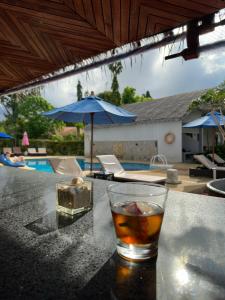 湄南海滩Adarin Beach Resort的坐在游泳池旁的桌子上喝一杯