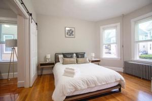 波士顿2 bedroom condo close to Boston and Cambridge with free parkings的卧室配有一张白色大床和两个窗户