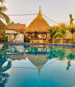 蓝梦岛Island Garden Huts Lembongan的茅草屋顶的度假游泳池