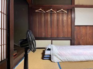 富士吉田市OSHI-KIKUYABO Mt-Fuji Historic Inn的配有风扇的客房位于床边