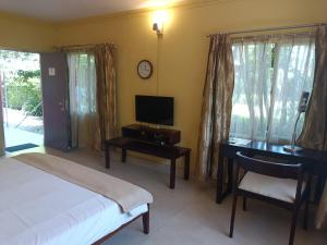 MākumChai Seeds Resort的一间卧室配有一张床、一张书桌和一台电视。