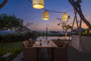 努沙杜瓦巴厘岛萨玛贝别墅酒店的天井上配有桌椅和灯光的餐桌