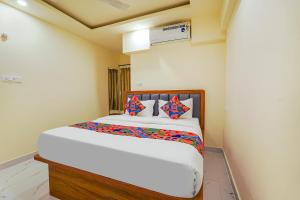 班加罗尔FabHotel Happy Home Stays的卧室配有一张带彩色枕头的大型白色床。