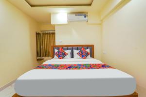 班加罗尔FabHotel Happy Home Stays的卧室配有一张带彩色枕头的大型白色床。