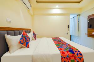 班加罗尔FabHotel Happy Home Stays的卧室配有白色的床和色彩缤纷的枕头