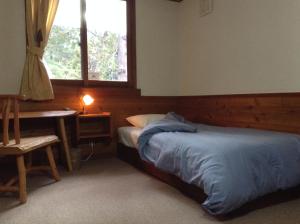 白马村瓦塔博时旅馆的一间卧室配有一张床、一张书桌和一个窗户。