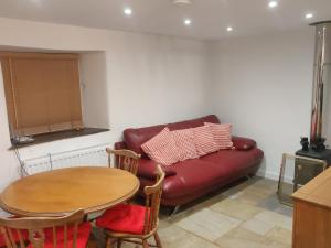 奇彭纳姆The Forge Kington St Michael的客厅配有红色的沙发和桌子