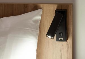 GenayB&B HOTEL Massieux Genay的一张带扬声器的床,旁边是白色枕头