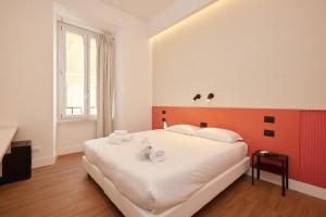 罗马DEM旅馆的一间卧室配有一张白色大床和橙色床头板