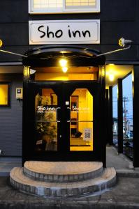 小樽Sho inn MINIMAL HOTEL 小樽駅から無料送迎あり的门上标有标志的商店前方