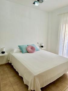 内尔哈Apartamento E&D的白色卧室配有一张大床,提供蓝色和粉红色的枕头