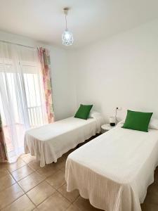内尔哈Apartamento E&D的客房设有两张床、白色床单和绿色枕头。