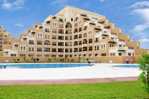 拉斯阿尔卡麦Hala Holiday Homes- Bab Al Bahr Residence, Al Marjan Island的一座大型建筑,前面设有一个游泳池