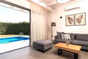 查加基恩Oresteia Exclusive Villa, a Sublime Retreat, By ThinkVilla的带沙发和桌子的客厅以及游泳池。
