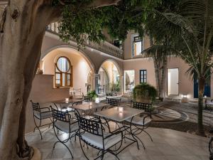 干尼亚卡萨德尔斐诺温泉酒店的庭院设有桌椅,棕榈树