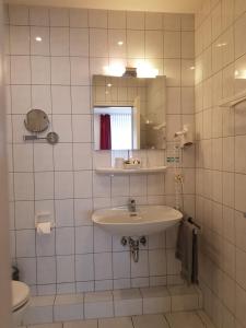 绍尔滕斯慕尼奈克酒店的白色瓷砖浴室设有水槽和镜子