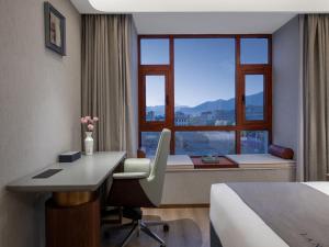 拉萨拉萨市政府西藏大学兰欧国际酒店的酒店客房设有一张桌子、一张床和一个窗户。