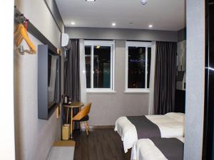 明光尚客优精选滁州明光星光商贸城酒店的酒店客房设有两张床、一张桌子和窗户。