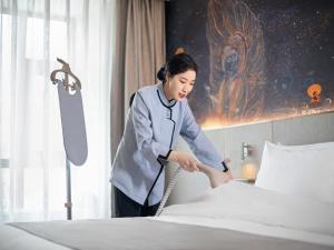 拉萨拉萨市政府西藏大学兰欧国际酒店的一位女性在旅馆房间做床