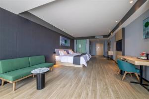 Shizuishan尚客优悦鄂尔多斯棋盘井镇政务服务中心酒店的酒店客房,设有一张床铺和一张绿色沙发