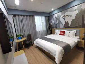 库尔勒尚客优精选库尔勒萨依巴格市场酒店的卧室配有一张大床,墙上挂有绘画作品