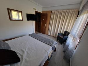 BeraLizuniaga的一间卧室配有一张床、一把椅子和电视