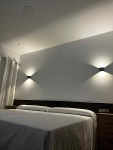 巴达霍斯Hotel Rural Irina的卧室配有一张带两盏灯的墙壁床。