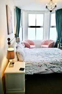 克里基厄斯Glan y Mor, Sleeps 20, 8 Bedrooms, 8 Bathrooms, Seafront, Criccieth的一间卧室配有一张床、一张桌子和两把椅子