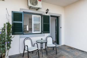 科梅诺Angelos Seaview Studios by Konnect, Kommeno Corfu的庭院设有两把椅子、一张桌子和一扇窗户。