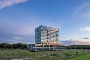 贝斯特Van der Valk Hotel Eindhoven-Best的田野中间的高大的玻璃建筑