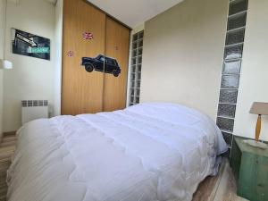 滨海伯内尔维尔Vue mer, 2 Pièces, balcon, parking privé.的卧室配有白色的床,墙上挂有汽车