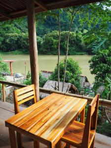NongkhiawMeexok river view的门廊上的木桌和椅子,享有美景