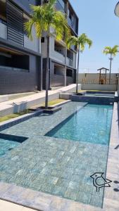 康德Cobertura Vista Mar Carapibus - Cariri Praia - Apartamento completo com 02 quartos的棕榈树建筑前的游泳池