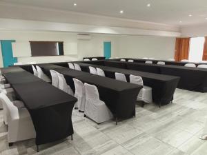 乌姆塔塔Adante Lodge & Conferencing的会议室配有黑桌和白色椅子