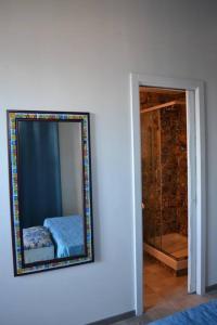 萨莱诺B&B Charming House的一面镜子在卧室旁边的墙上