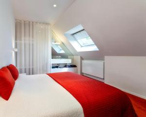 布兰肯贝赫Polderlicht的卧室配有红色和白色的床,设有天窗