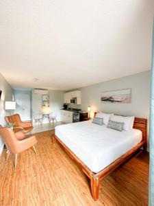 沃萨加比奇海滩Oasis by the Bay Vacation Suites的卧室配有一张白色大床和一把椅子