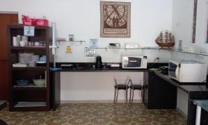 瓜鲁雅Parque Suites Com Ar Condicionado Piscina e Estacionamento的厨房配有带2张凳子的台面和微波炉