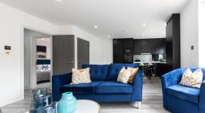 斯坦斯LUXURIOUS Apartments FREE parking and FREE WiFi!的一间带2张蓝色沙发的客厅和一间厨房