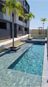 康德Cobertura Vista Mar Carapibus - Cariri Praia - Apartamento completo com 02 quartos的一座楼前棕榈树游泳池