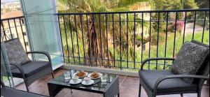 卡拉德米哈斯Apartment Summer Vibes Miraflores - La Cala de Mijas的阳台配有两把椅子和一张桌子,还有一棵树