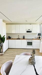 慕尼黑Neubau stilvolle Dachgeschoss City Wohnung的厨房配有白色橱柜和一张桌子及雕像