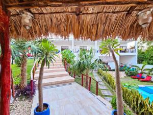 巴利亚多利德Mayan Majesty Boutique Hotel的一条棕榈树和茅草屋顶的小路