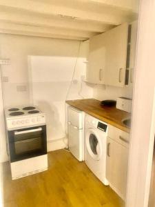 伦敦Large self-contained cozy studio的小厨房配有炉灶和洗衣机。