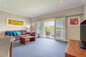 亚林加普Caves House Hotel Apartments的一间带紫色沙发的客厅和一个阳台
