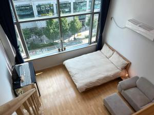 首尔Hongdae Station loft apartment的客房设有床、椅子和窗户。